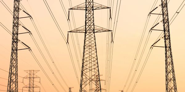 High-voltage power lines and pylons at sunset.