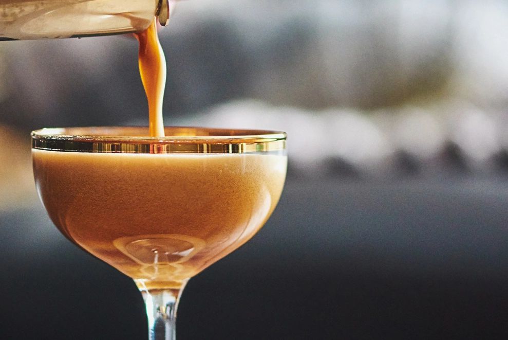 Coffee being poured into a glass with a gold rim.