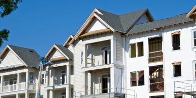A row of houses under construction with scaffolding and blue sky.