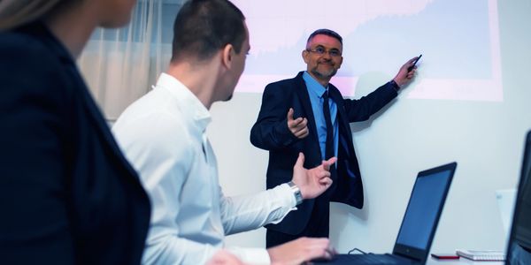 Businessman presenting financial growth chart to colleagues in a meeting.