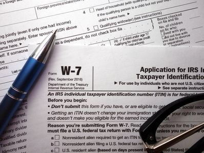 IRS Form W-7 with a pen and glasses on top.