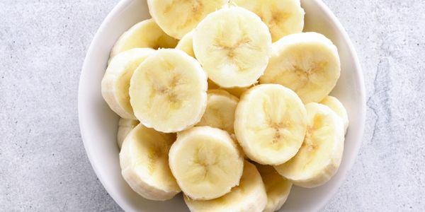 A bowl filled with fresh banana slices on a light surface.