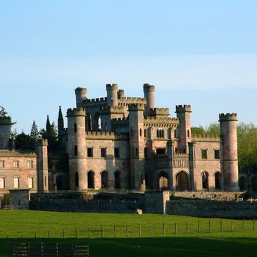 Historic castle with multiple towers under clear blue sky.