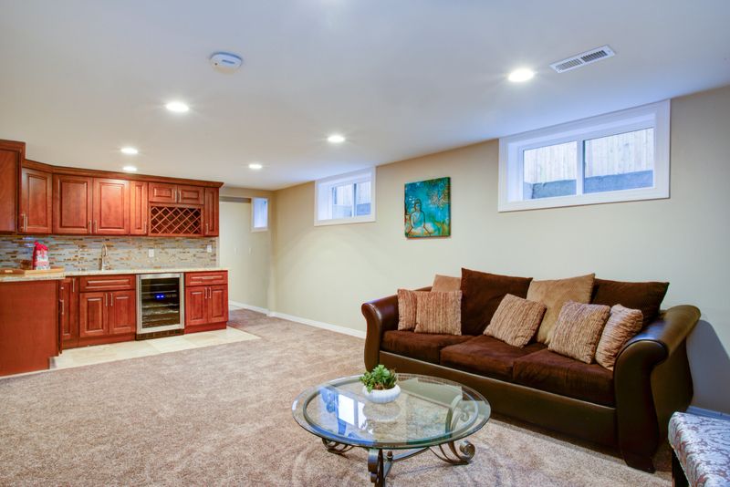 Stunning basement interior boasts a nice wet bar composed of wood shaker cabinets with granite countertop and a mosaic backsplash.