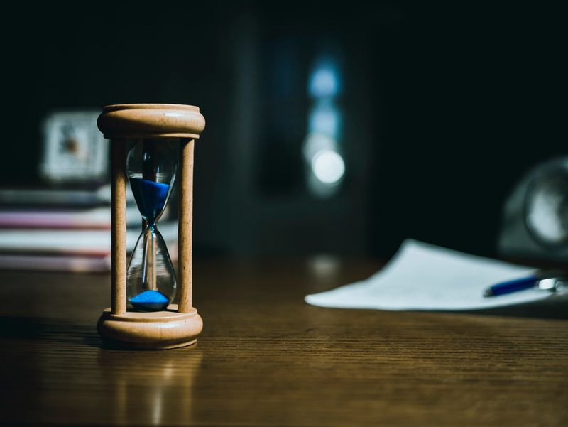 close up of hourglass on the table, blurry background