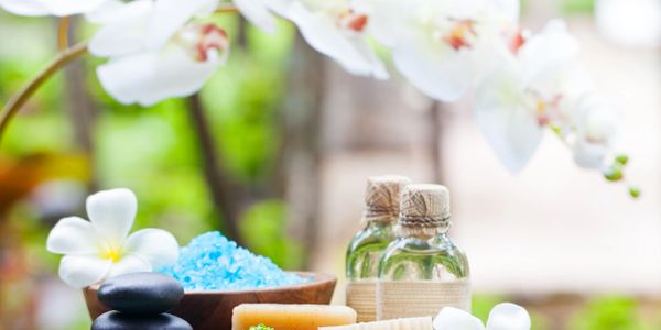 Spa essentials with flowers, stones, and bath salts creating a calming scene.