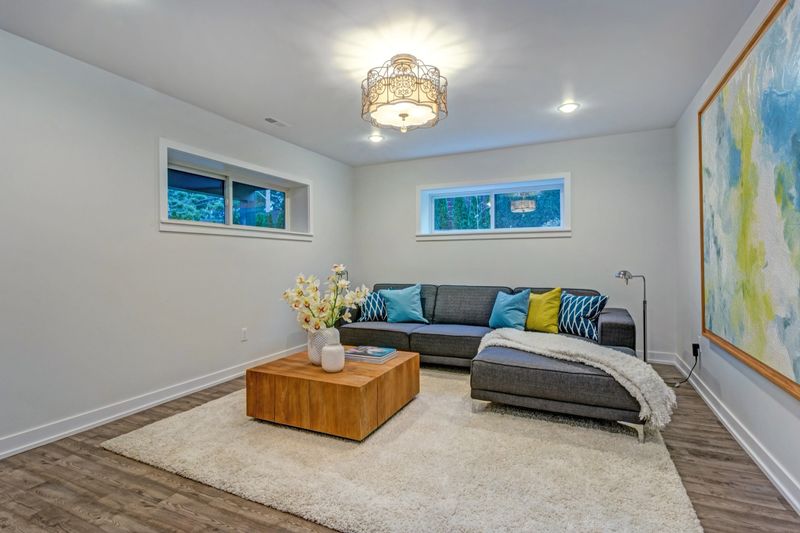 Bright colorful modern family room interior with wood accents, blue pillows on the sofa and large abstract art piece on the wall.