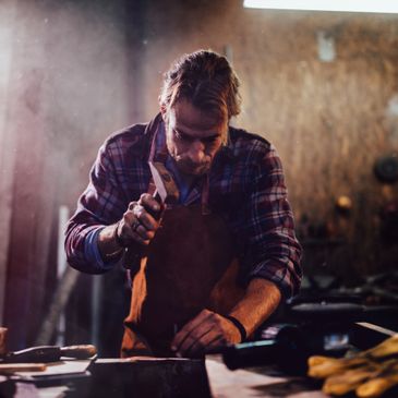 A focused craftsman working with a hammer in a workshop.