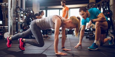 Woman doing mountain climber exercise with trainer support.