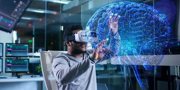 Man using VR headset to interact with a holographic brain model in high-tech lab.