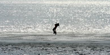 A person jumping mid-air over a shimmering water surface.