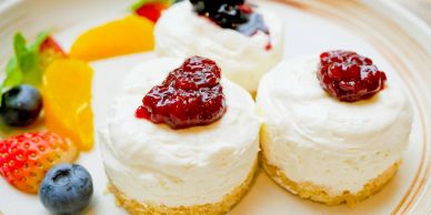 Mini cheesecakes topped with berry jam and fresh fruits on the side.
