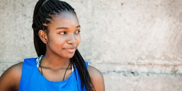 Young woman in a blue sports jersey looking to the side with a subtle smile.
