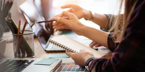 people working on a project utilizing notepads and laptop computers 