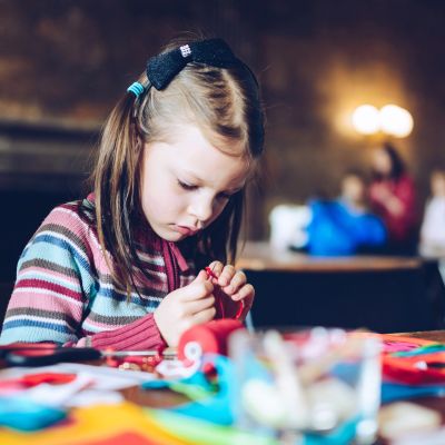 Little girl focused on arts and crafts at a table.