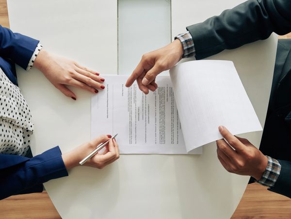 Two people reviewing and signing a document at a table.