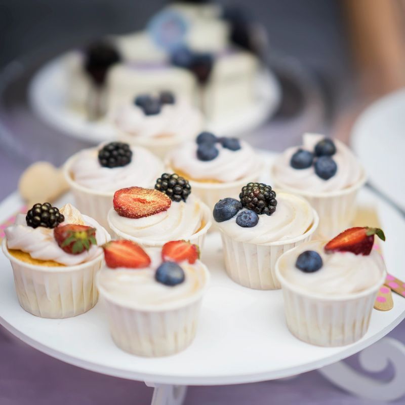Different appetizing tartlets, cake basket with white cream and fresh multi-colored berries, summer dessert.