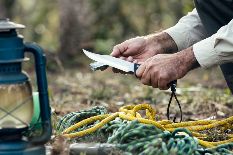 Man hands sharpening knife outdoors in the wilderness
