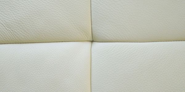Close-up of white leather upholstery with textured stitching.