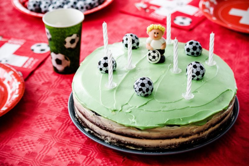 Kids birthday party Football theme. Chocolate cake decorated like football field with seven candles.