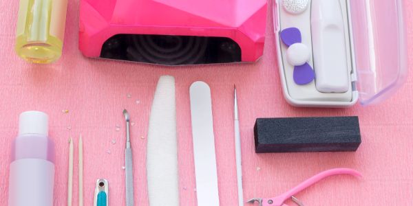 Set of nail care tools on a pink surface.