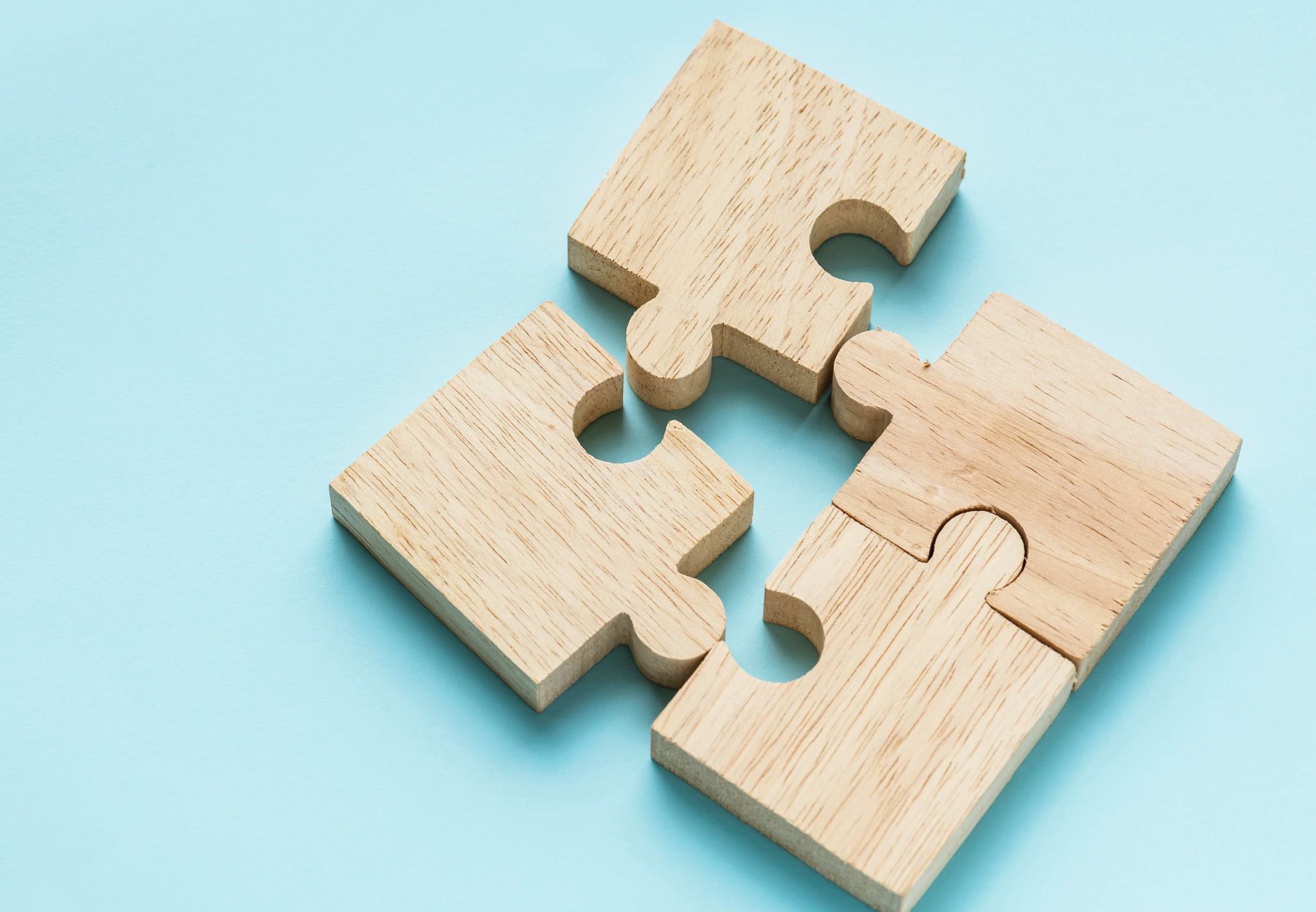 Four wooden puzzle pieces on a light blue background