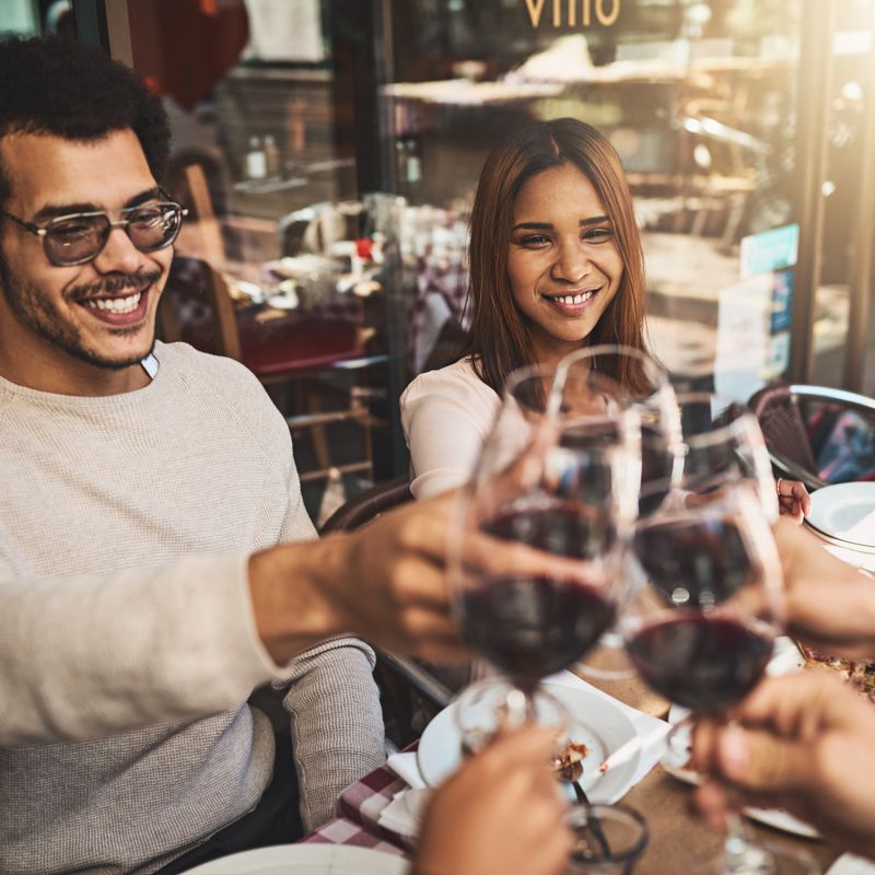 Shot of a group of cheerful young friends having a celebratory toast with wine at dinner inside of a restaurant