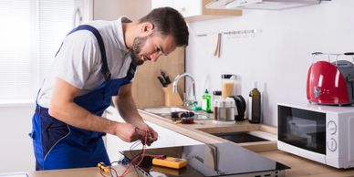 Technician repairing an electric stove in a modern kitchen.