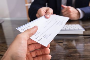 Person handing over a check to another person.