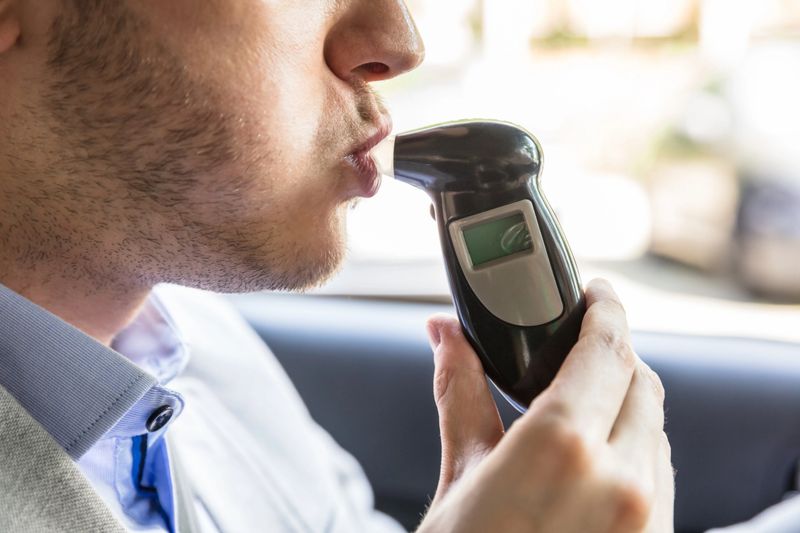 Close-up Of A Young Man Sitting Inside Car Taking Alcohol Test