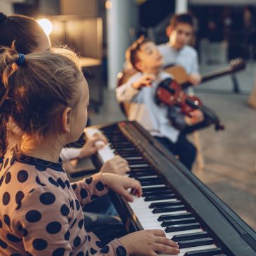 Children playing piano and violin in a music class.