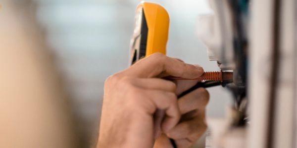 Hand testing or fixing electrical outlet with a tool.