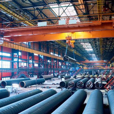 Large industrial warehouse with metal pipes and an overhead crane with API Q1 compliance