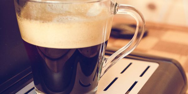 A glass cup of espresso coffee with crema on top.