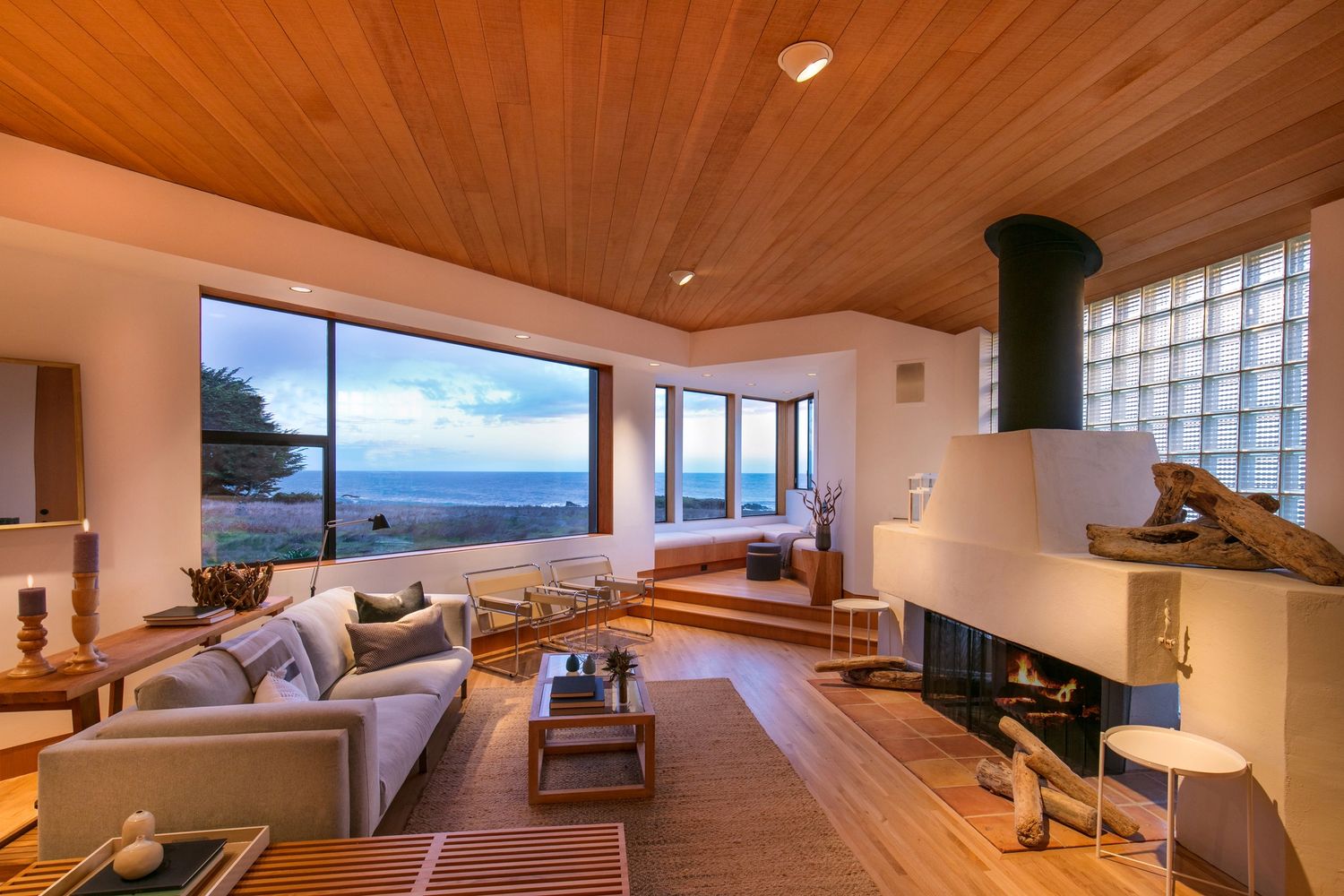 Open floor plan living room with ocean view modern fireplace and natural elements.