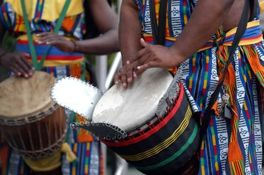 Close-up of musicians playing colorful drums with vibrant attire.