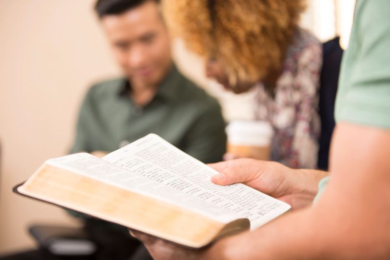 Multi-ethnic, mixed age group of people involved in Christian bible study meeting at local church.
