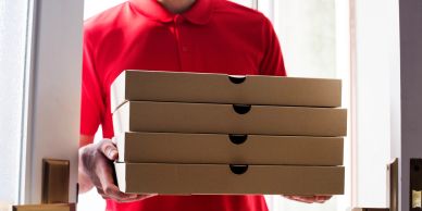 Delivery person holding pizza boxes at door.