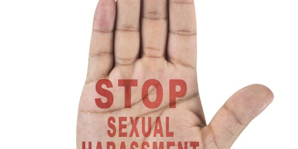 A raised hand with the words "STOP SEXUAL HARASSMENT" written on the palm.