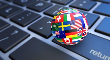 A globe with various international flags on a computer keyboard.