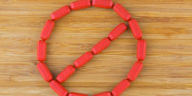 Red pills arranged to form a prohibition symbol on a wooden surface.