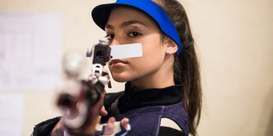 Woman aiming with a rifle indoors.