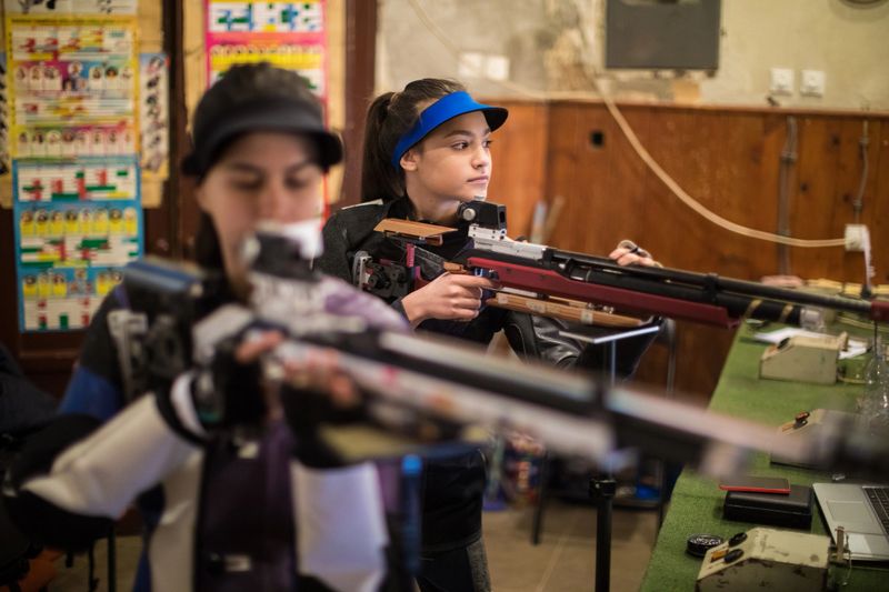 Young caucasian women practicing with sporting guns at shooting range