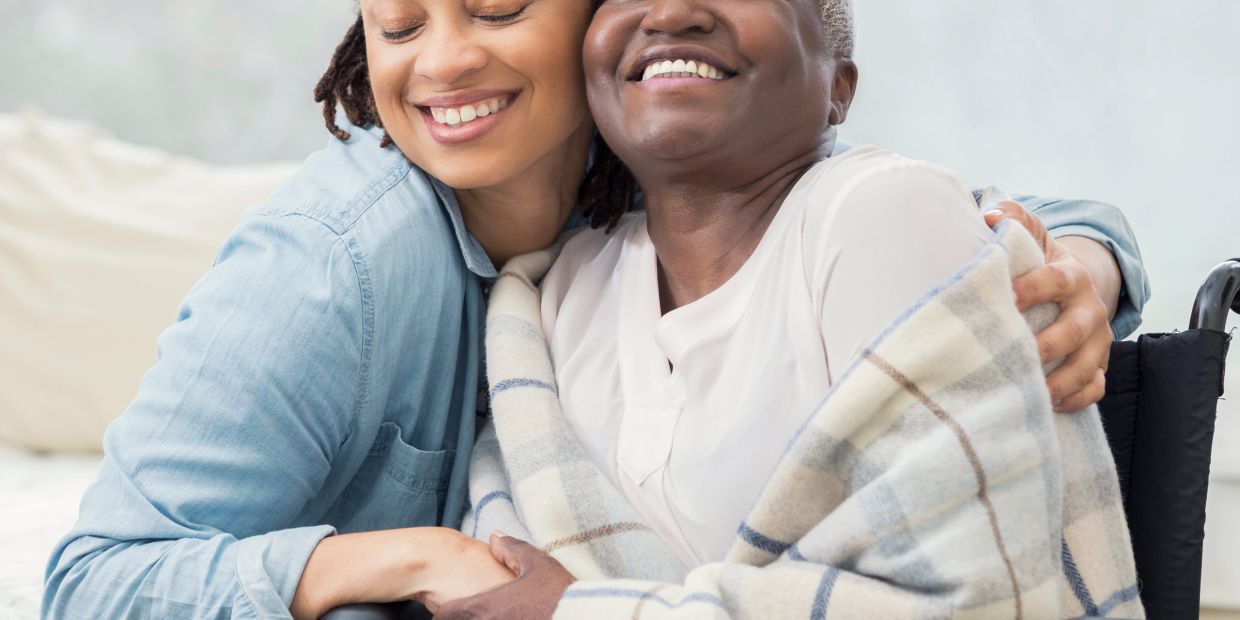 Two women sharing a warm hug, one in a wheelchair.