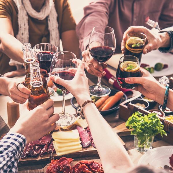 Friends toasting with drinks over a table filled with food.