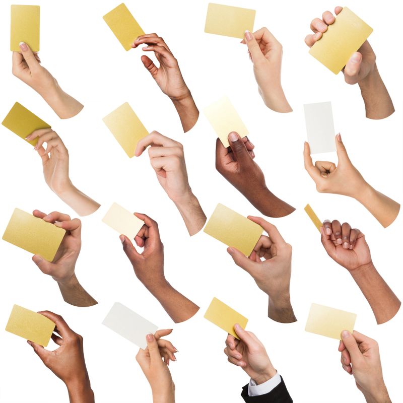 Multiethnic diverse hands holding empty business cards with copy space. Caucasian and african-american, men and women. Isolated at white background