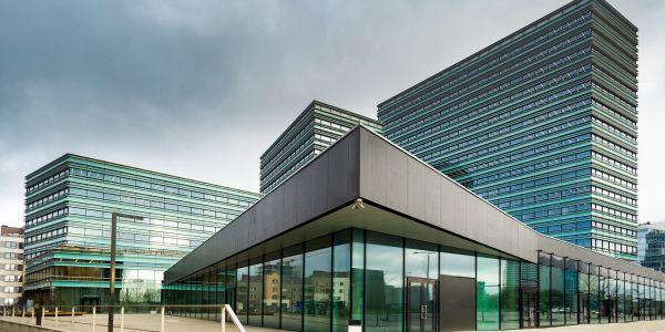 Modern glass office buildings under a cloudy sky.