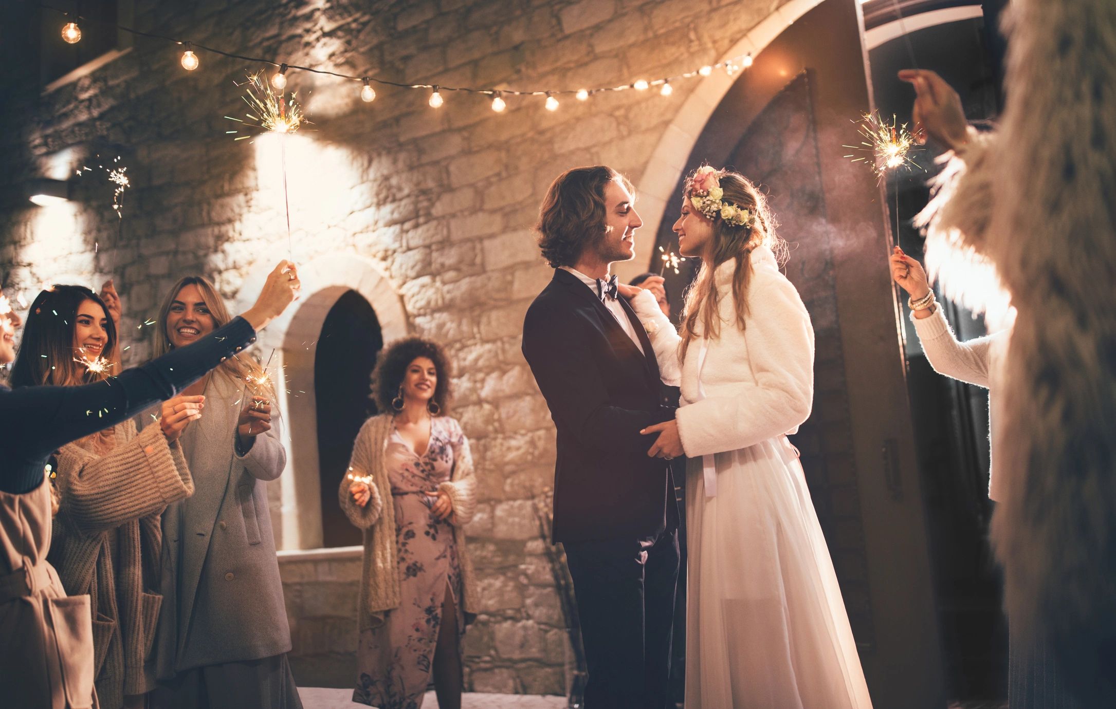 Couple celebrating with sparklers surrounded by friends.