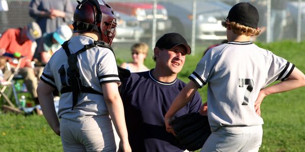 Baseball coach talking to players during a game.