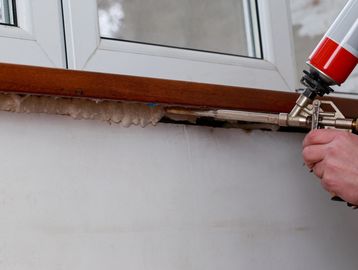 Sealing around a window with single part gun foam to prevent air leakage.